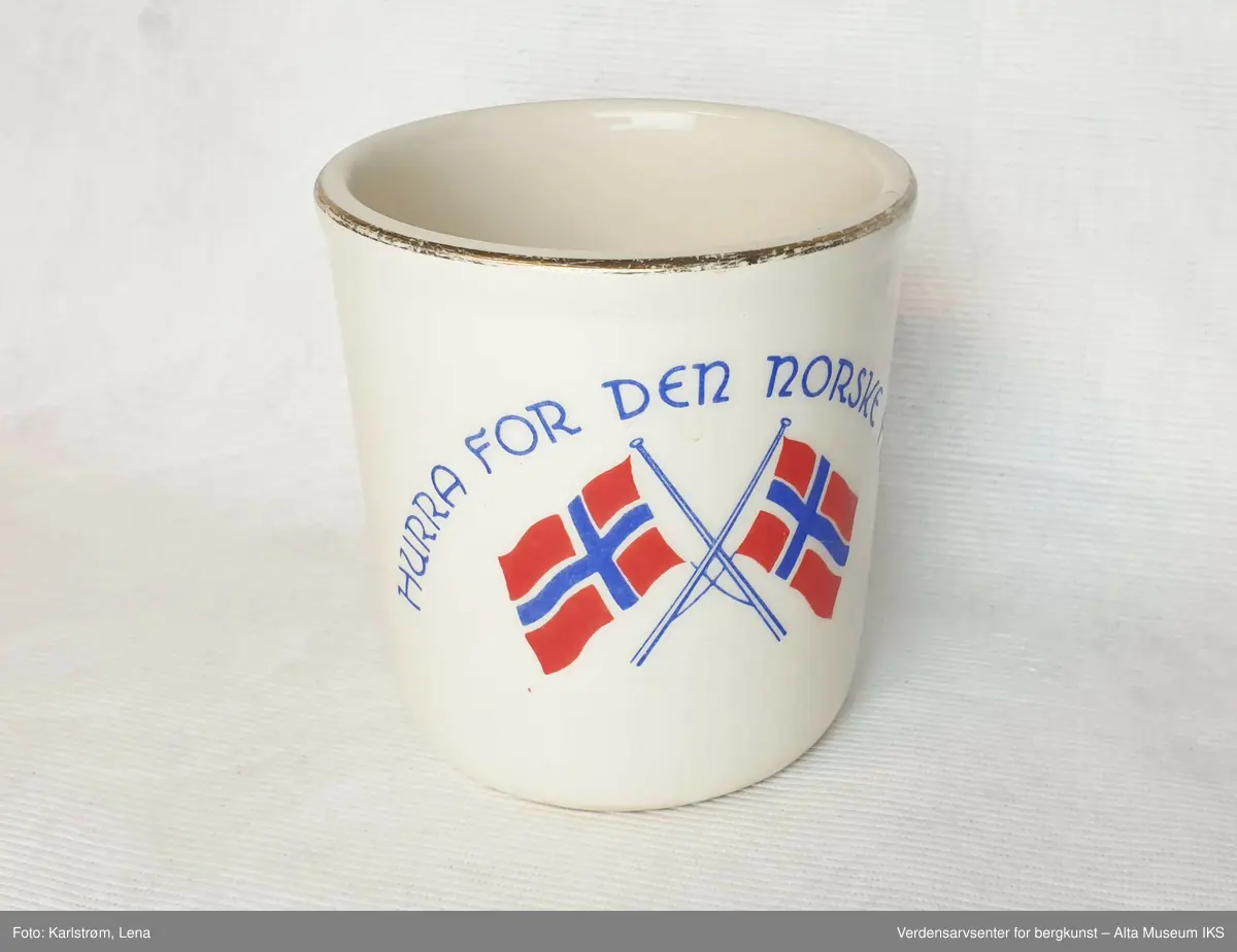 Kopp i hvitt porselen dekorert med gullkant, to norske flagg og teksten "Hurra for den norske fisker"