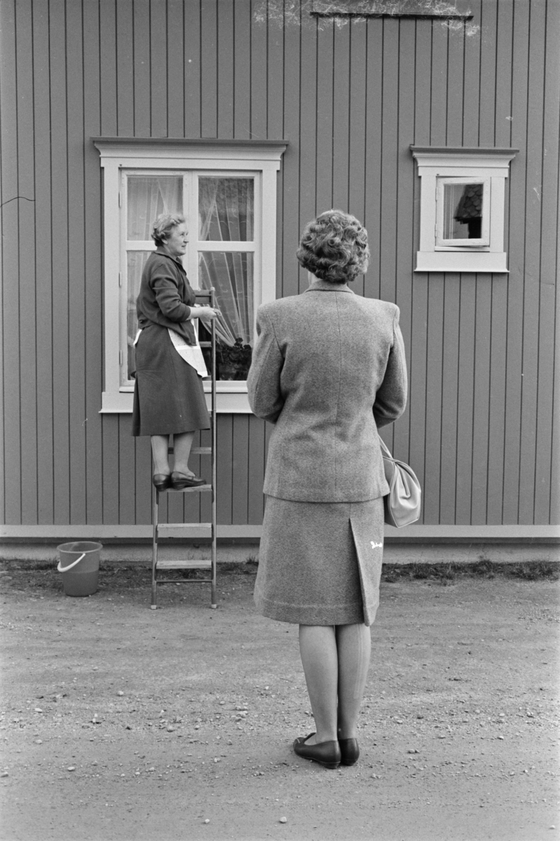 To kvinner i en gate på Røros. En pusser vinduer.