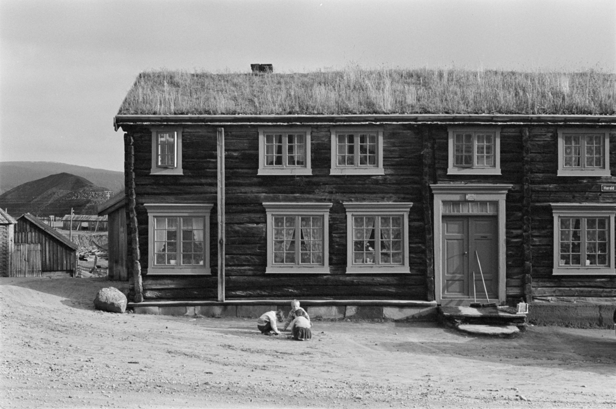 Barn leker foran et laftet tømmerhus på Røros.