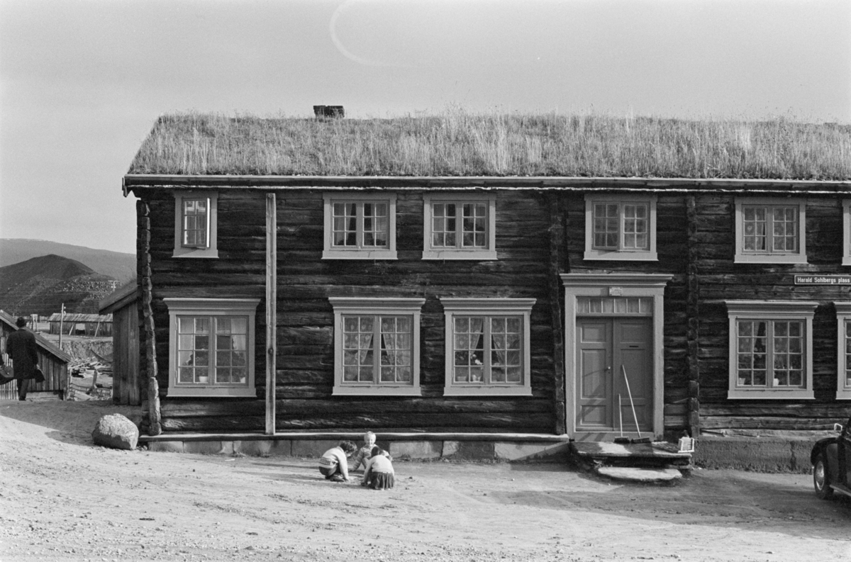 Barn leker foran et laftet tømmerhus på Røros.