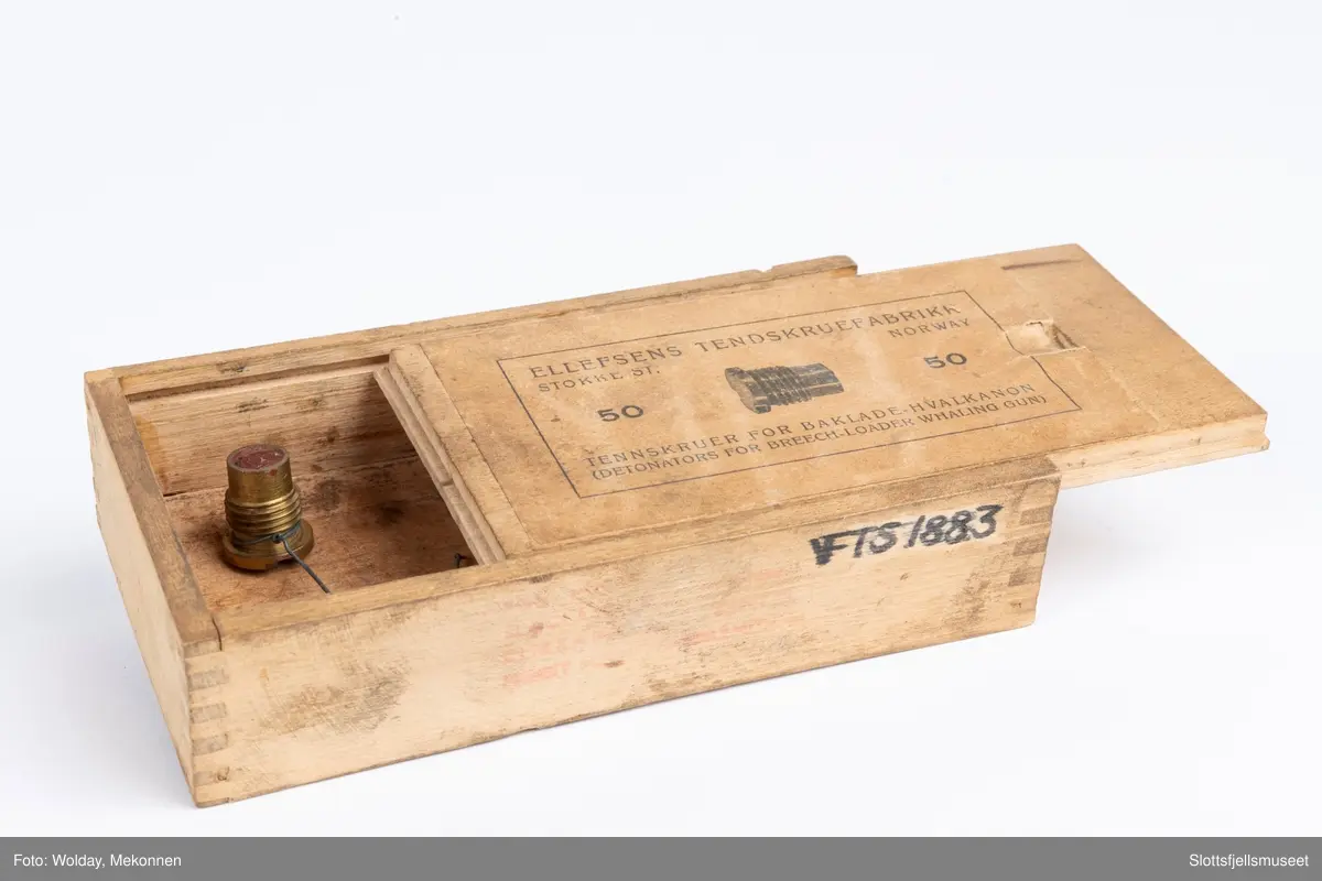 Treeske med skyvelokk, papirmerke med følgende påskrift (trykk): ELLEFSENS TENDSKRUEFABRIKK, STOKKE ST., NORWAY. 50 TENNSKRUER FOR BAKLADE-HVALKANON (DETONATORS FOR BREECH-LOADER WHALING GUN), samt bildet av en tennskrue.
Esken inneholder dessuten én stk tennskrue.