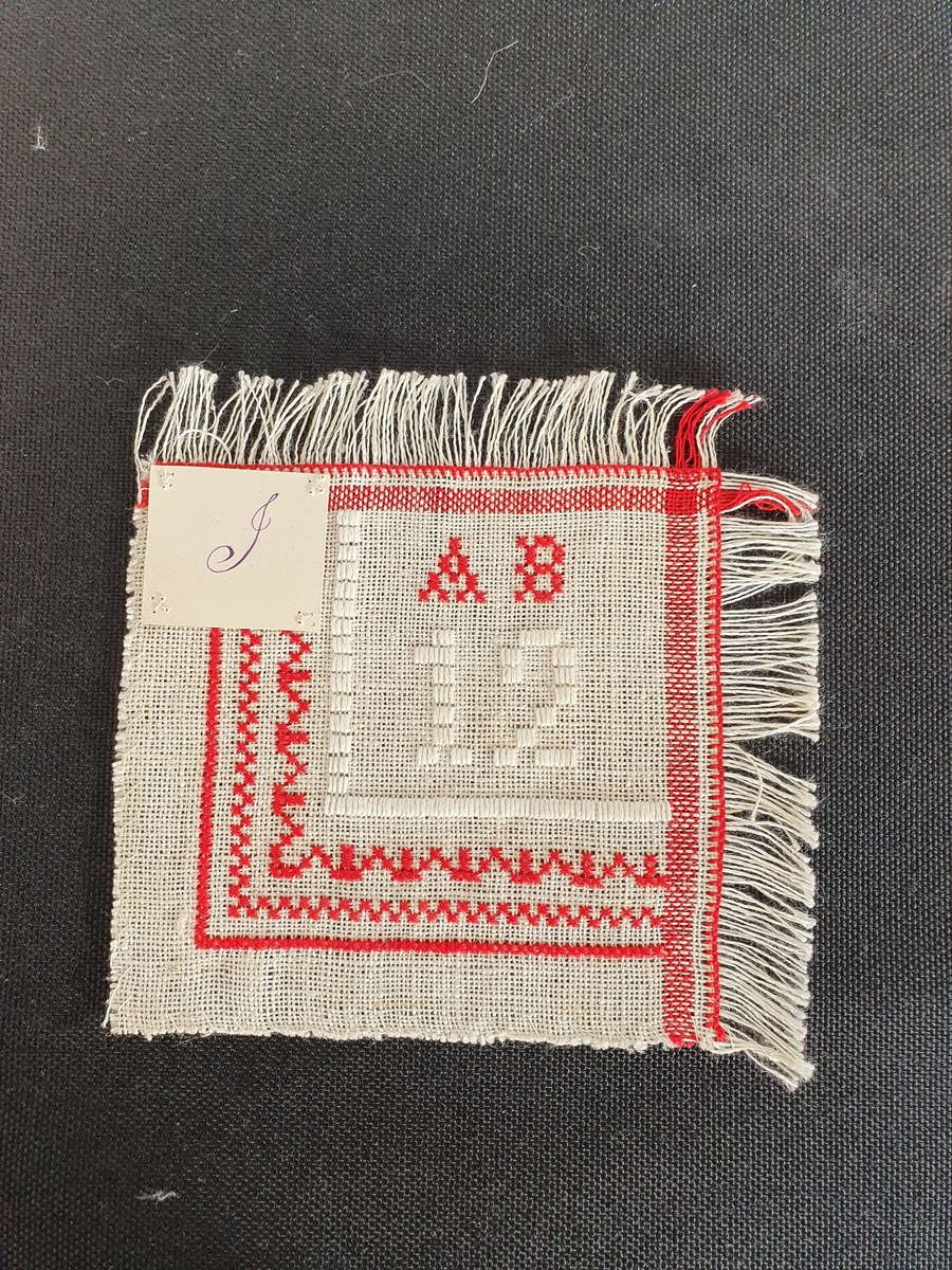 Tøy og kant som på HH.1981-0064

Med rødt bomullsgarn "AB" og tre border med korssting.
Med hvitt bomullsgarn "12" og to border i bunnsøm.
Frynsekant på to sider, kastet på to.

Har tilhørt givers mann, politimester i Hamar, Reidar T.R. Beichmann, født i Trondheim 1884, død Hamar 1959. Tekstilene er utført av hans tanter Ragnhild og Aagot Beichmann. Ragnhild var malerinne, f.1854, og i 1874-77 utdannet hos Knut Bergslien i Christiania, og 1877-79 hos Carl Gussow i Berlin. Hun malte hovedsakelig portretter. I sine senere år var hun meget syk. Aagot Beichmann har utdannelse som håndarbeidslærinne ved Kvindelig Industriskole i Christiania 1892. Opplyser giver.
Fru Agnes Beichmann bodde i Børstadalleén 5, Hamar etter at hun ble enke. Flyttet i november 1981 til Østregate 122.
