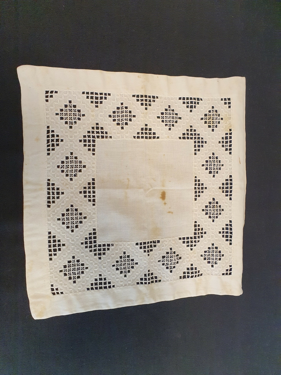 Bomull, sultan, hvit.
Brodert bord langs falden: Hardanger og hullsøm "Hedebosøm"
Rustflekker.