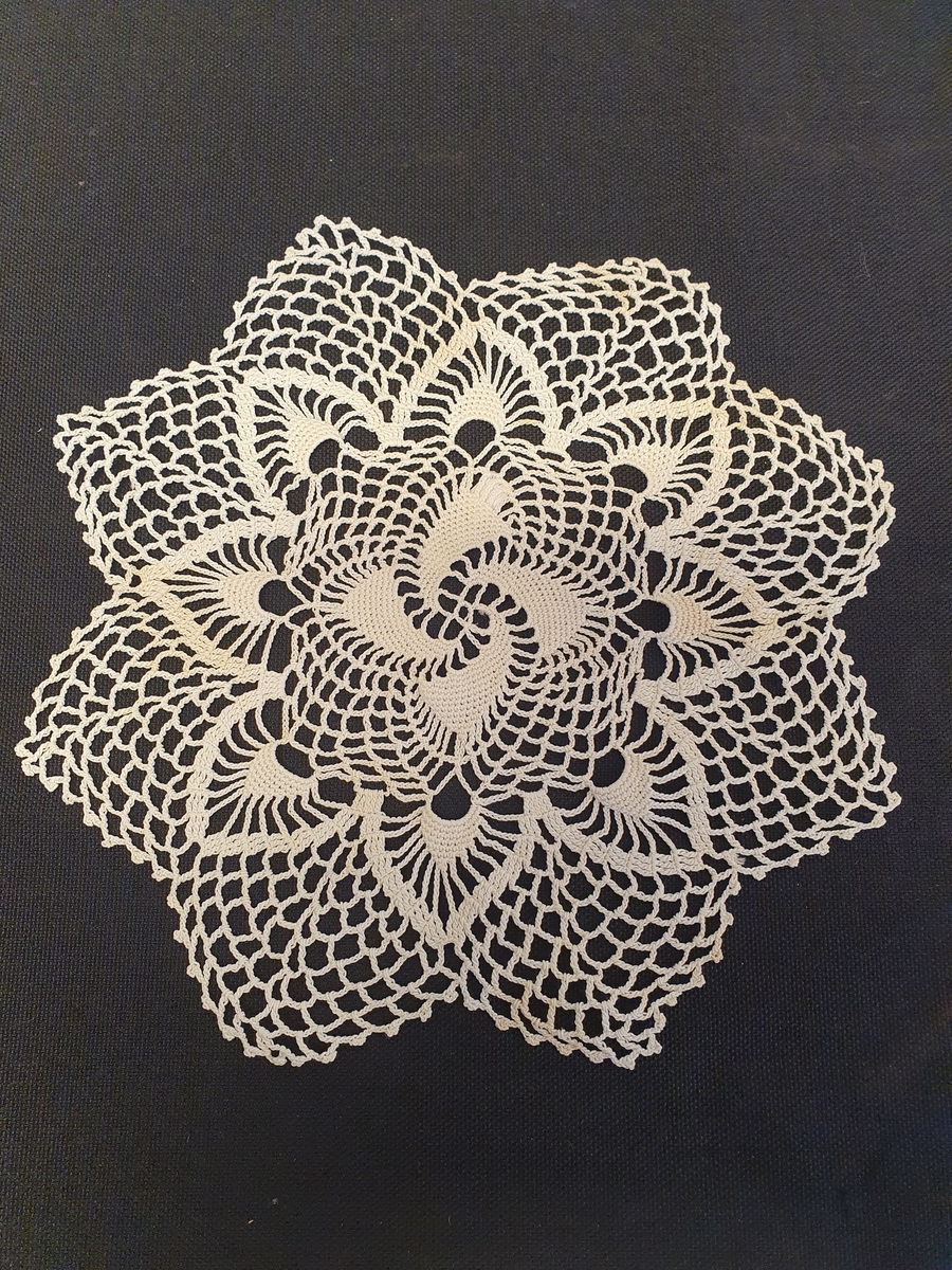 Heklet, hvit.
Gjennombrutt mønster, rose på midten.
Takkekant ytterst.
Rustflekker.