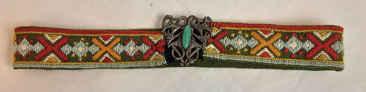 Bunadsliv og belte. Brodert mønster i ullgarn. Beltespenne med grønn sten.