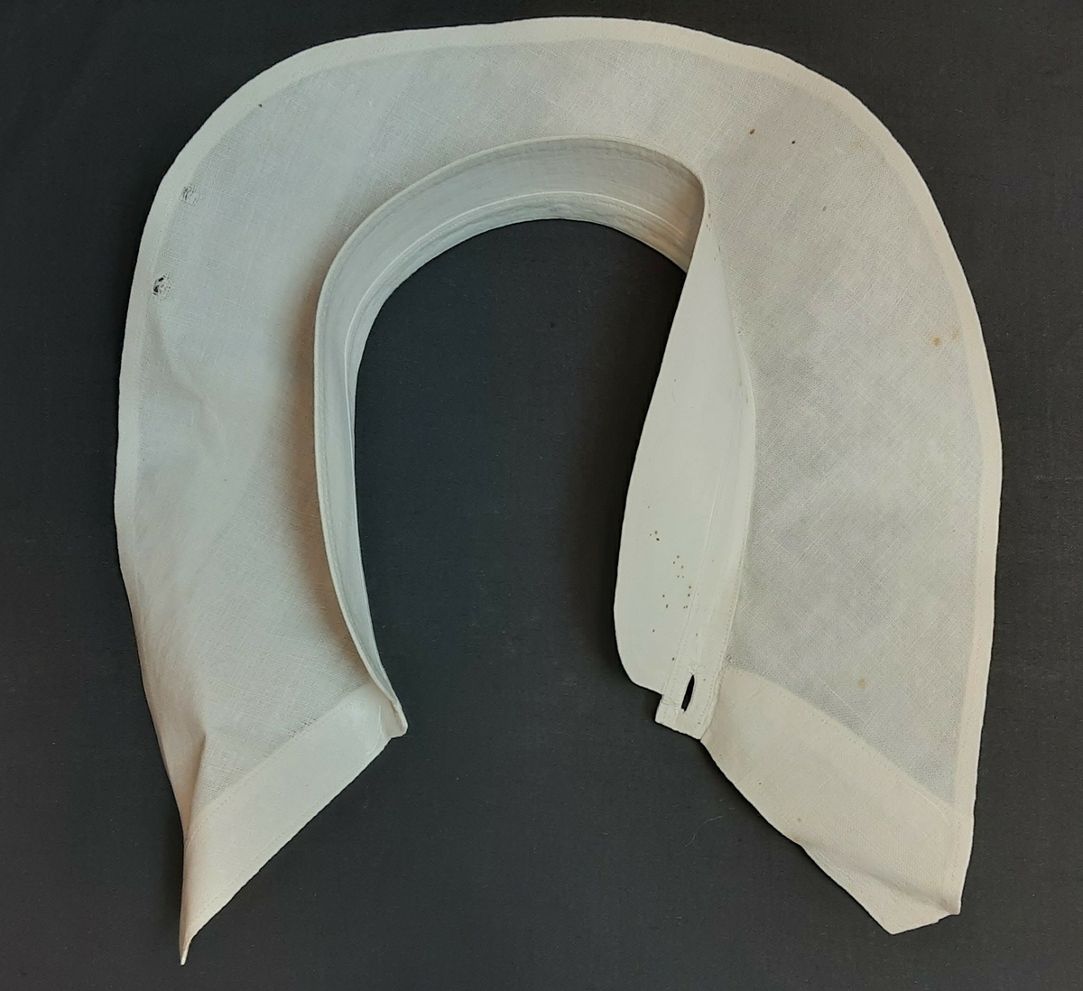 Stivet snipp. Knapping foran. Buet krage. Har krageskjørt