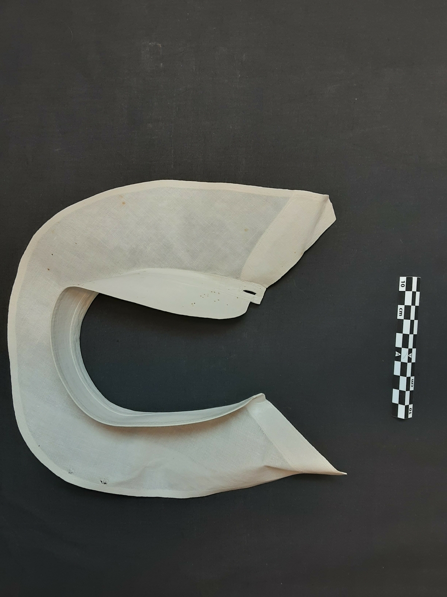 Stivet snipp. Knapping foran. Buet krage. Har krageskjørt