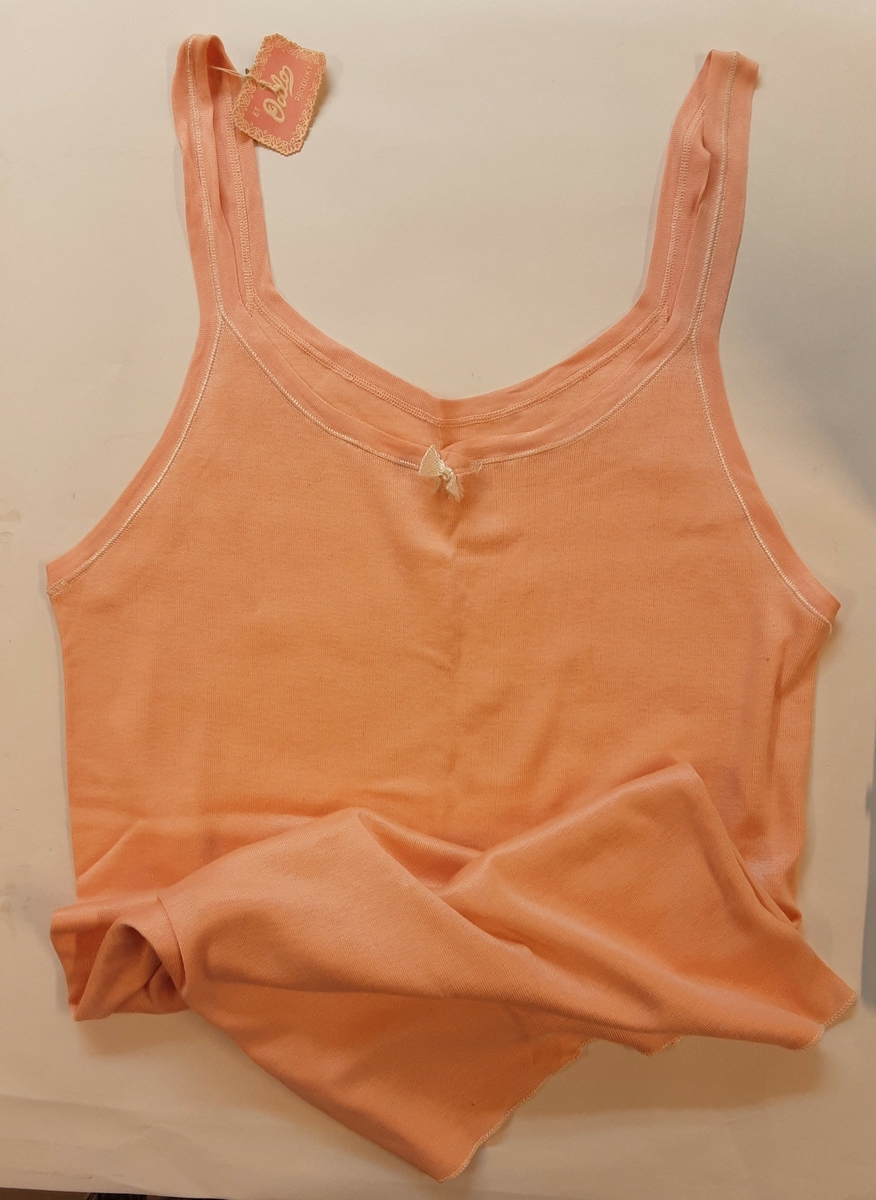 Dametrøye i trikot med smale stropper over skuldrene. Silkesøm. Liten sløyfe i utringningen. Elastisk. Størrelse 46.
Produsert av Odlo, trolig 1940-50-tallet.