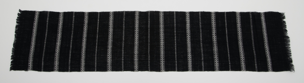 Svart vevd løper med innvevde striper i hvitt; regelmessig annenhver stripe med hvitt mønster og annenhver stripe med 2 hvite innslag.