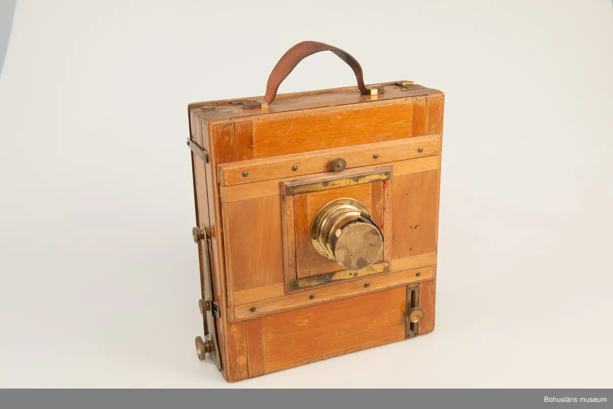 Kamerahuset tillverkat i mahogny med bälg i svart textil och läderhandtag med företagets namn inpräglat.
Kameran har ett dubelanastigmatiskt objektiv monterat,  tillverkat av C. P Goerz i Berlin med en brännvidd på 240 mm och en bländare som kunde ställas in mellan 1:4,8 och 1:384. Slutaren som monterades på objektivet saknas idag. Objektivet märkt: P G GOERTZ BERLIN DOPFEL ANASTIGMATER. Ett sammetsklätt objektivskydd i papp.
Till kameran hör UM034203 Stativ i fodral, UM034204 Objektiv och UM034205-UM034206 Ram.