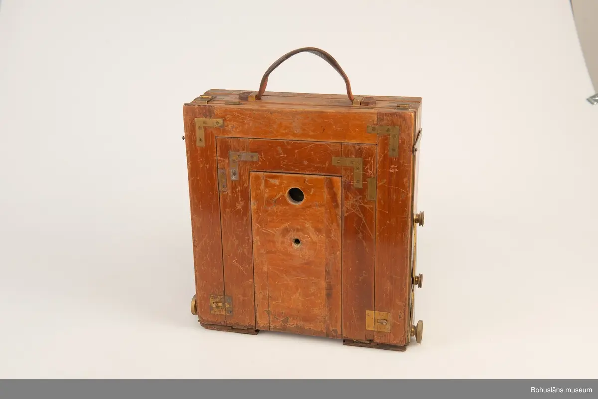 Kamerahuset tillverkat i mahogny med bälg i svart textil och läderhandtag med företagets namn inpräglat.
Kameran har ett dubelanastigmatiskt objektiv monterat,  tillverkat av C. P Goerz i Berlin med en brännvidd på 240 mm och en bländare som kunde ställas in mellan 1:4,8 och 1:384. Slutaren som monterades på objektivet saknas idag. Objektivet märkt: P G GOERTZ BERLIN DOPFEL ANASTIGMATER. Ett sammetsklätt objektivskydd i papp.
Till kameran hör UM034203 Stativ i fodral, UM034204 Objektiv och UM034205-UM034206 Ram.