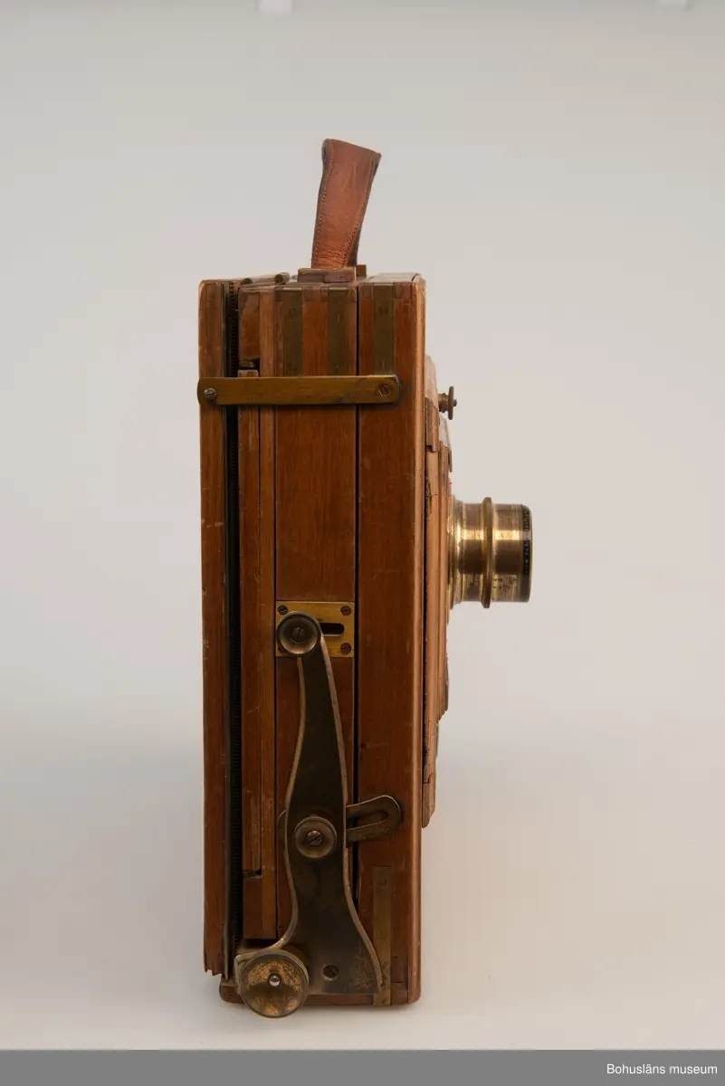 Kamerahuset tillverkat i mahogny med bälg i svart textil och läderhandtag med företagets namn inpräglat.
Kameran har ett dubelanastigmatiskt objektiv monterat,  tillverkat av C. P Goerz i Berlin med en brännvidd på 240 mm och en bländare som kunde ställas in mellan 1:4,8 och 1:384. Slutaren som monterades på objektivet saknas idag. Objektivet märkt: P G GOERTZ BERLIN DOPFEL ANASTIGMATER. Ett sammetsklätt objektivskydd i papp.
Till kameran hör UM034203 Stativ i fodral, UM034204 Objektiv och UM034205-UM034206 Ram.