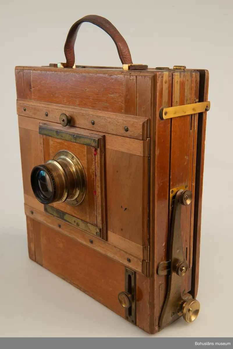 Kamerahuset tillverkat i mahogny med bälg i svart textil och läderhandtag med företagets namn inpräglat.
Kameran har ett dubelanastigmatiskt objektiv monterat,  tillverkat av C. P Goerz i Berlin med en brännvidd på 240 mm och en bländare som kunde ställas in mellan 1:4,8 och 1:384. Slutaren som monterades på objektivet saknas idag. Objektivet märkt: P G GOERTZ BERLIN DOPFEL ANASTIGMATER. Ett sammetsklätt objektivskydd i papp.
Till kameran hör UM034203 Stativ i fodral, UM034204 Objektiv och UM034205-UM034206 Ram.