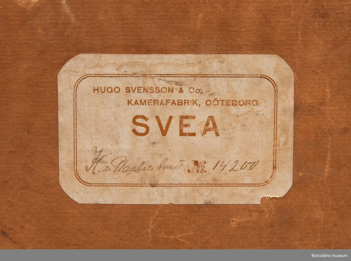 Svart fallplåtskamera av märket SVEA med kamerahus i svart metall. Handtag av läder med inpräglad text: MANUFAKTUR HUGO SVENSSON GÖTENORG
Medföljande originalkartong med klisteretikett: 
HUGO SVENSSON & CO, KAMERAFABRIK, GÖTEBORG
SVEA
NO 14 200