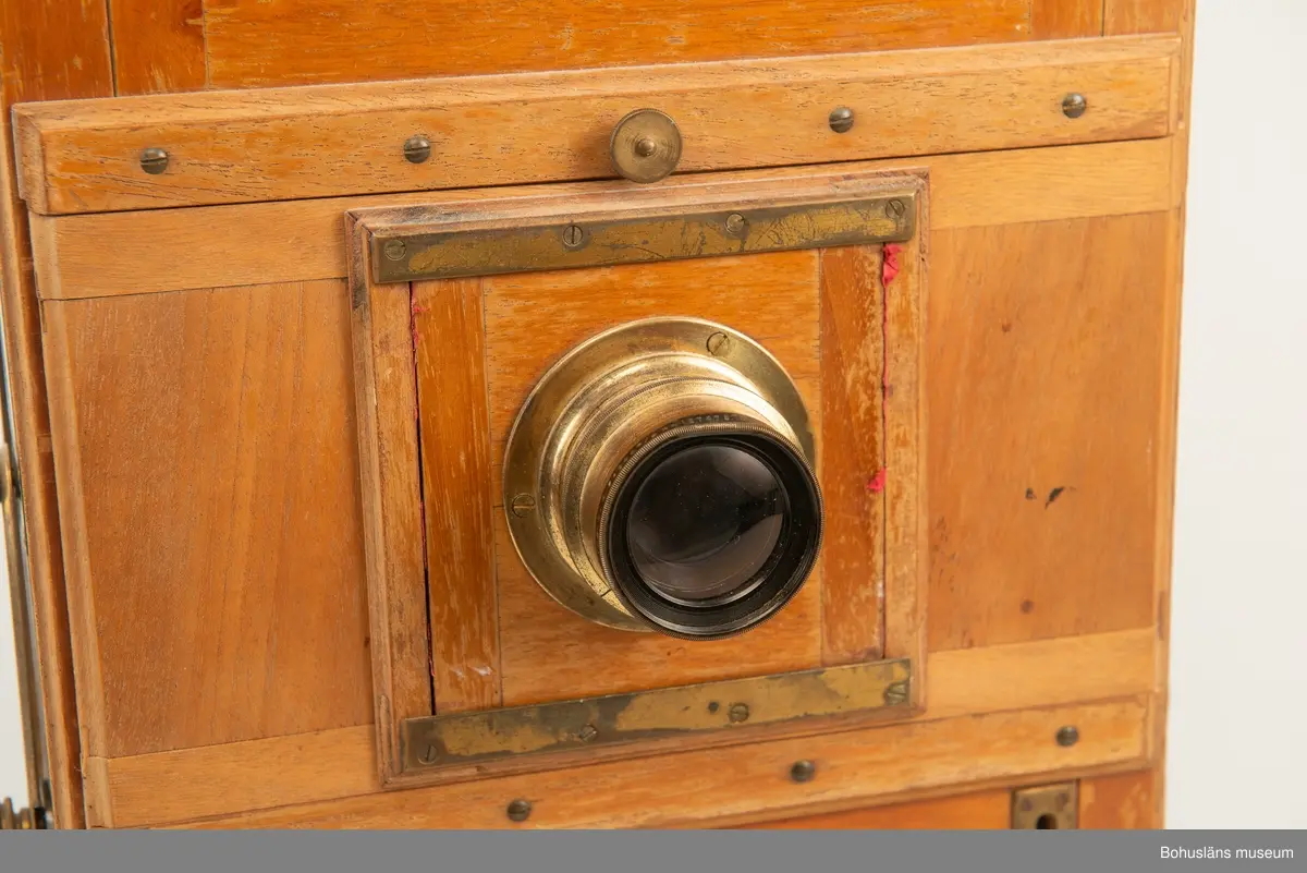 Kamerahuset tillverkat i mahogny med bälg i svart textil och läderhandtag med företagets namn inpräglat.
Kameran har ett dubelanastigmatiskt objektiv monterat,  tillverkat av C. P Goerz i Berlin med en brännvidd på 240 mm och en bländare som kunde ställas in mellan 1:4,8 och 1:384. Slutaren som monterades på objektivet saknas idag. Objektivet märkt: P G GOERTZ BERLIN DOPFEL ANASTIGMATER. Ett sammetsklätt objektivskydd i papp.
Till kameran hör UM034203 Stativ i fodral, UM034204 Objektiv och UM034205-UM034206 Ram.