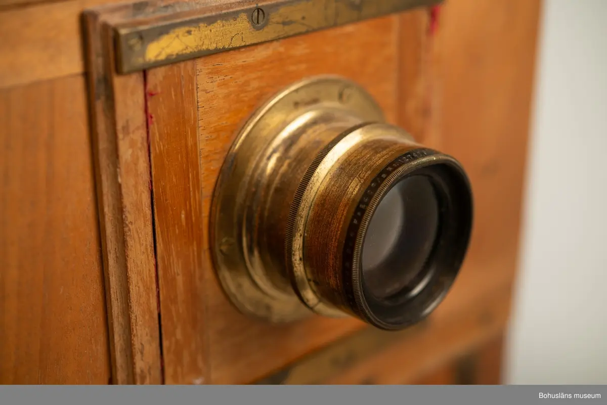 Kamerahuset tillverkat i mahogny med bälg i svart textil och läderhandtag med företagets namn inpräglat.
Kameran har ett dubelanastigmatiskt objektiv monterat,  tillverkat av C. P Goerz i Berlin med en brännvidd på 240 mm och en bländare som kunde ställas in mellan 1:4,8 och 1:384. Slutaren som monterades på objektivet saknas idag. Objektivet märkt: P G GOERTZ BERLIN DOPFEL ANASTIGMATER. Ett sammetsklätt objektivskydd i papp.
Till kameran hör UM034203 Stativ i fodral, UM034204 Objektiv och UM034205-UM034206 Ram.