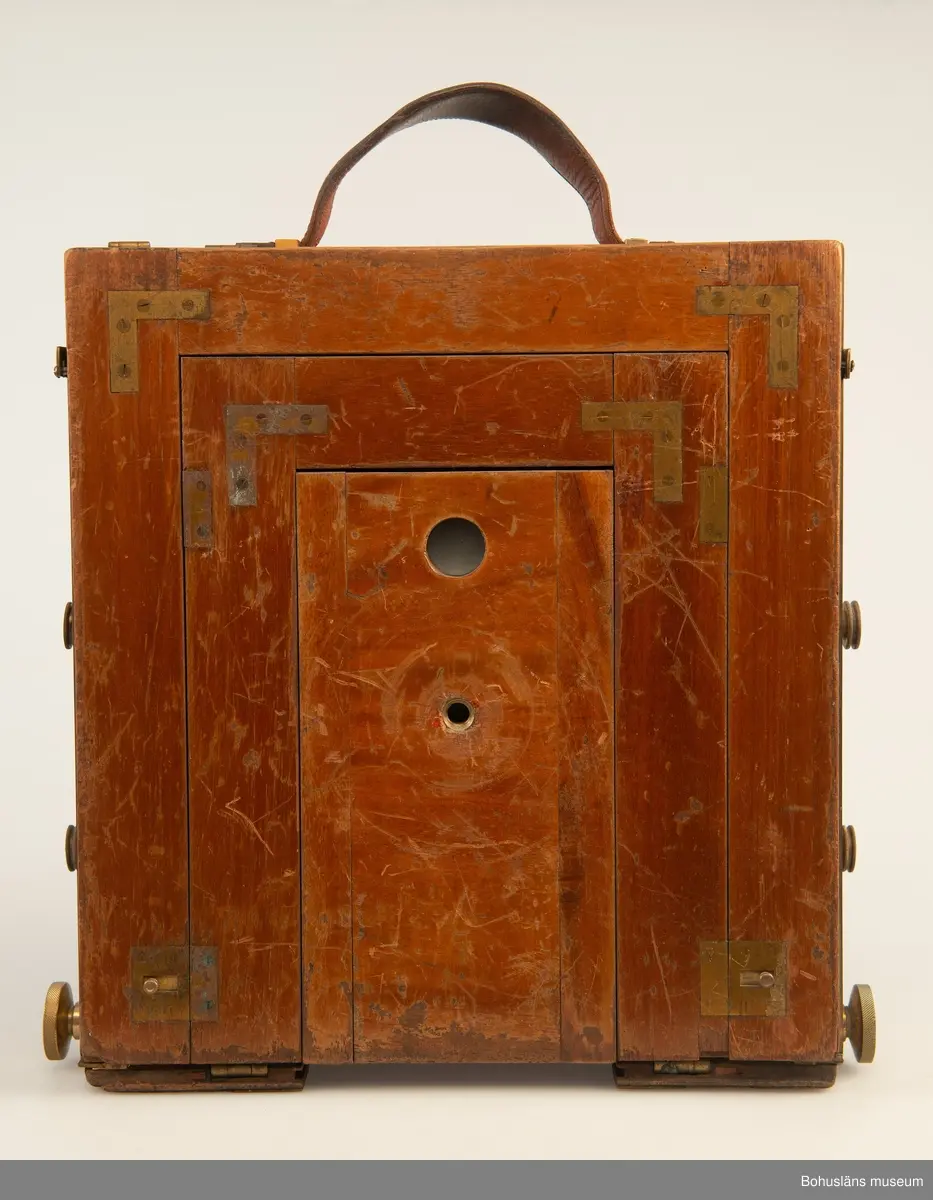 Kamerahuset tillverkat i mahogny med bälg i svart textil och läderhandtag med företagets namn inpräglat.
Kameran har ett dubelanastigmatiskt objektiv monterat,  tillverkat av C. P Goerz i Berlin med en brännvidd på 240 mm och en bländare som kunde ställas in mellan 1:4,8 och 1:384. Slutaren som monterades på objektivet saknas idag. Objektivet märkt: P G GOERTZ BERLIN DOPFEL ANASTIGMATER. Ett sammetsklätt objektivskydd i papp.
Till kameran hör UM034203 Stativ i fodral, UM034204 Objektiv och UM034205-UM034206 Ram.