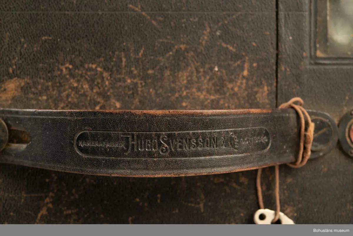 Svart fallplåtskamera av märket SVEA med kamerahus i svart metall. Handtag av läder med inpräglad text: MANUFAKTUR HUGO SVENSSON GÖTENORG
Medföljande originalkartong med klisteretikett: 
HUGO SVENSSON & CO, KAMERAFABRIK, GÖTEBORG
SVEA
NO 14 200
