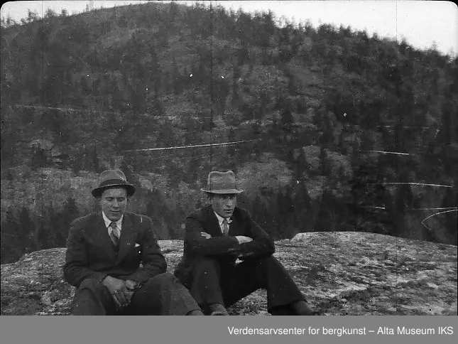 2 menn med dress og hatt sitter på et fjell.