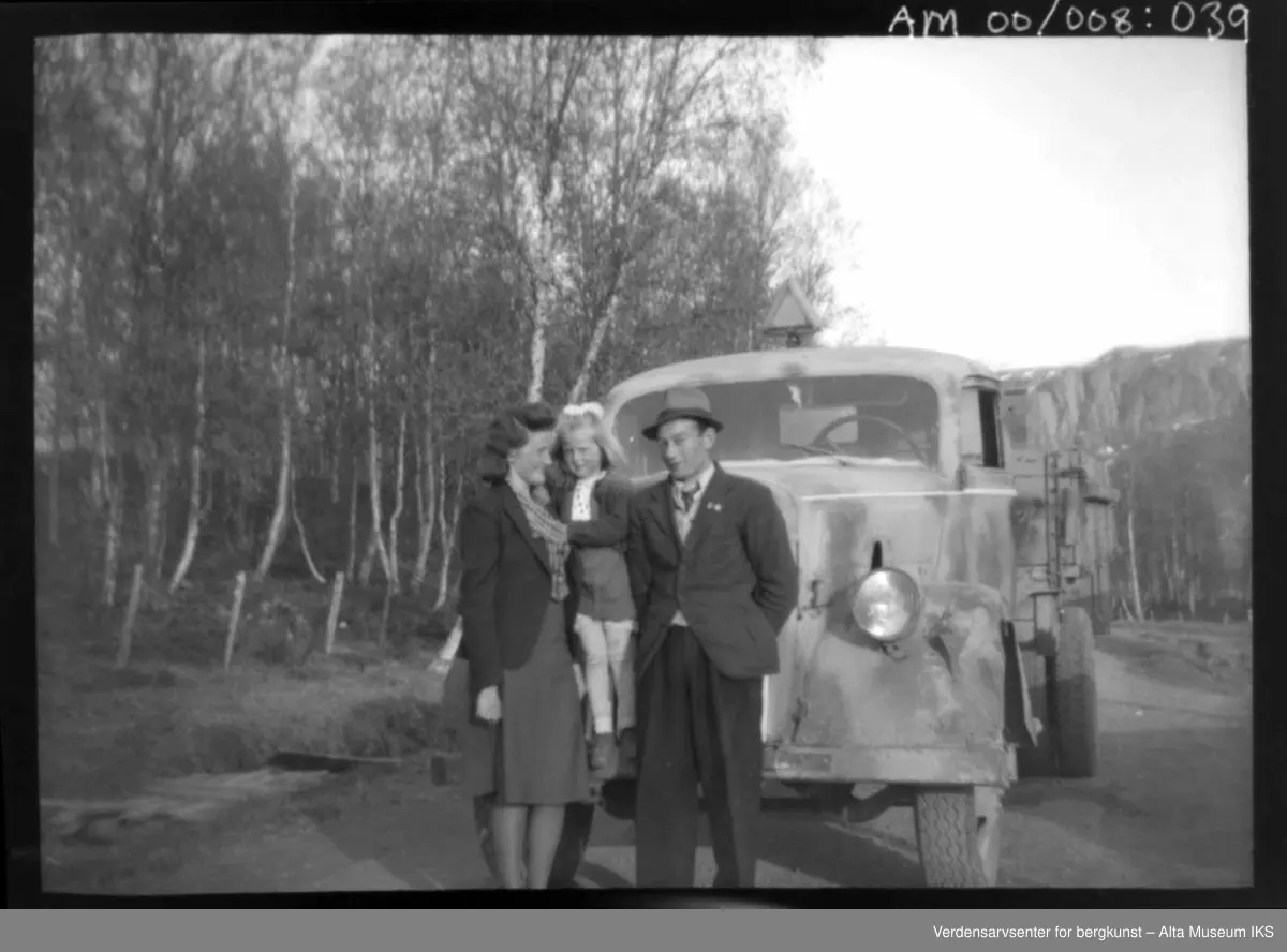 Kvinne med barn og mann ved en lastbeil.