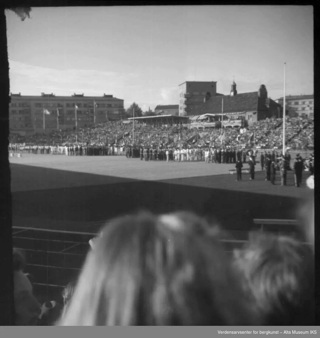 Musikkorps og flere idrettslag står oppstillt under Nord Atletisk Mesterskap i Oslo med fullsatt stadion.