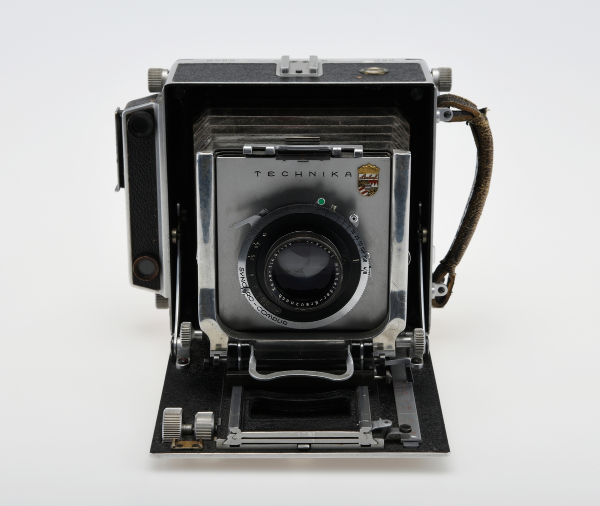 Et storformat belgkamera for plater på 9x12cm fra Linhof, med et 150mm fastobjektiv. Linhof er i dag den eldste kameraprodusenten i verden som fortsatt produserer kameraer etter at Gandolfi og Kodak sluttet deres produksjon.    

Foran på kameraet er det en luke som kan åpnes opp for å dra fram belgen som er festet på en skinne på innsiden av luken. Belgen kan flyttes fram og tilbake på skinnen, og objektivplaten kan også flyttes sideveis, i høyden eller tippes bakover. Objektivet og lukkerhuset er montert på en avtagbar plate i front av belgen. På lukkerhuset er det et hjul for å stille inn lukkertiden og en liten spake for å justere blenderåpningen. 

På baksiden av kameraet er det en luke til filmplater med en mattskive inni. På luken er det en svart solskjerm som kan brettes ut. På den en siden av kamerahuset er det en søker med en rammesøkermekanisme koblet til fokusmekanismen foran på belgskinnen. Søkeren har en holder til en blitslampe. På toppen av kamerahuset er det en tilbehørssko og et vater. Kameraet er dekket i svart skinn. Håndtak i skinn på siden. kameraet har stativfester både under kamerahuset og under luken til belgen.