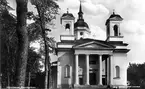 Härnösands domkyrka. Vykort. Arkitekt Johan Adolf Hawerman. Nyklassistisk stil. Vitputsad stenkyrka med ett mittorn, två mindre torn och västfasad med pelarrad. En del inventarier från den äldre kyrkan bland annat altartavlan från 1700-talet.Treskeppigt kyrkorum. Orgel från 1731 av Johan Caliman med barockfasad av Magnus Granlund från Hudiksvall