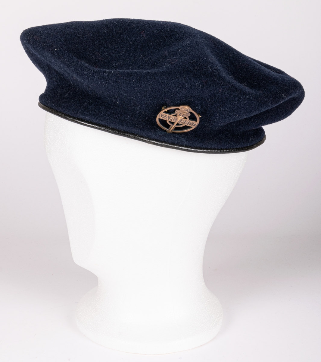 Blå filtbasker med läderkant. I sidan en metallpin "Var redo". Invändigt tryck: The Scout Shop, Trade Mark "Boy scouts" KANGOL, Cleaton Cumberland".
Storlek 7½/58.
Tejpbit med texten M. Ehrnberg, Bomhus.