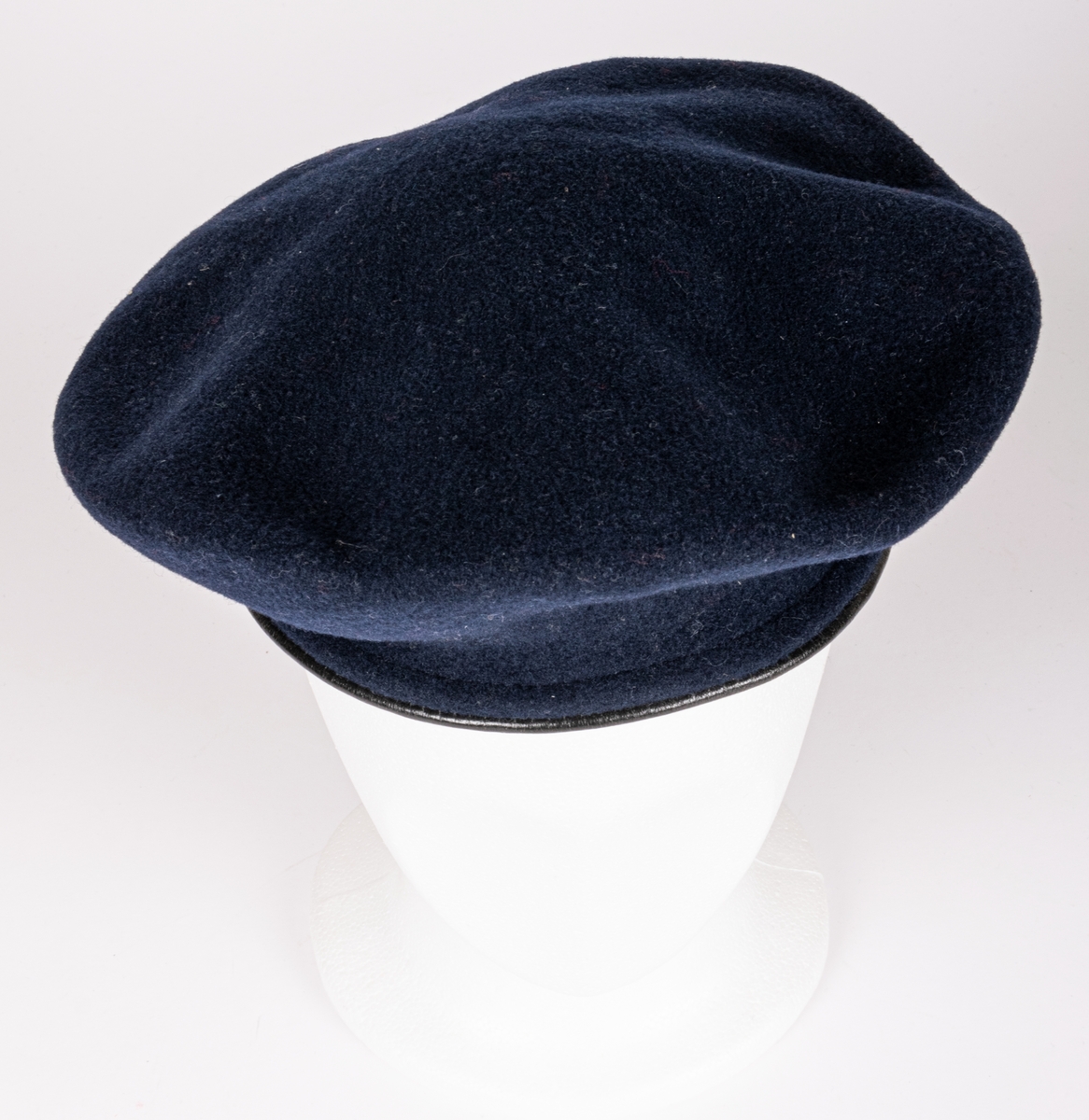 Blå filtbasker med läderkant. I sidan en metallpin "Var redo". Invändigt tryck: The Scout Shop, Trade Mark "Boy scouts" KANGOL, Cleaton Cumberland".
Storlek 7½/58.
Tejpbit med texten M. Ehrnberg, Bomhus.