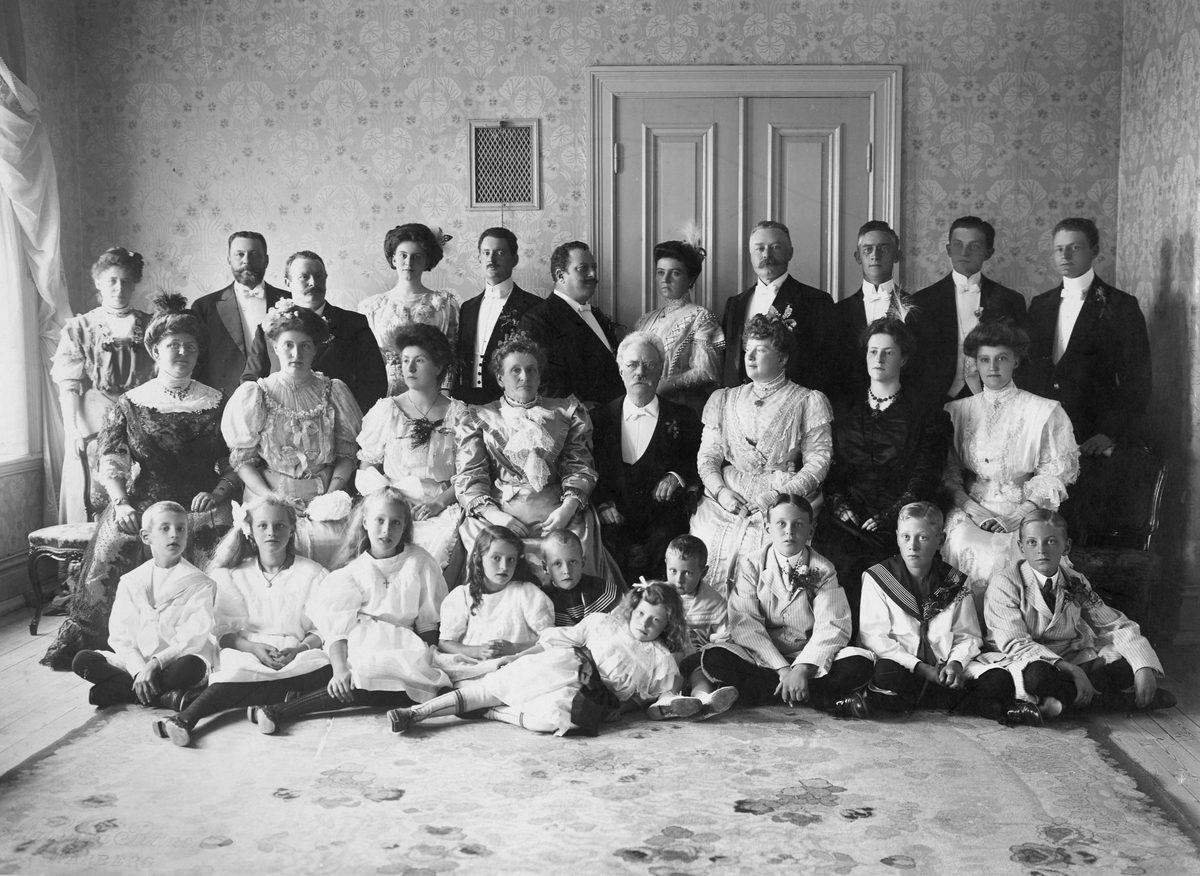 Gruppbild av familj och släkt när skräddaremästare Jean Svensson och hustrun Maries guldbröllop firades den 15 augusti 1908. Jubilarerna sitter i mitten med döttrarna Emma och Anna till höger om Jean, Olga och Julia till vänster om Marie. Längst ut till vänster sitter Katy, gift med sonen Emil, och längst till höger sitter Ellen Svensson, f Elmqvist. Baktill från vänster står sönerna Emil (Jordan Swensson), Ivan, Knut, Otto med hustrun Kristin och längst till höger Otto (Jordan Swensson) och Hugo. (Sonen Hjalmar är inte med på bilden.) Herrarna närmast till höger om Kristin är Bror Axel Rosander t v och Curt Geier t h. Längst till vänster står Ivans fru Helena Svensson och deras dotter Ann-Marie ligger längst fram. Emils dotter Kristin står som nummer fyra från vänster.
Barnen sittande fr v: Hugo Welander, Viola Rosander, Mia Rosander, Ebba Geier, Oscar Emil Rosander, Otto Geier, Stuart Jordan Swensson, Jean Rosander, Henry Jordan Swensson.

De är samlade i ett stort rum med stormönstrad jugendtapet med löv och blommor och en stor matta på golvet. Jean var bror till borgmästaren Emil Svensson i Varberg så guldbröllopet uppmärksammades i staden bland annat med flaggning i hamnen. Ett konditori hade skänkt tårtan till festen, en krokan med "brudparet" avbildat på toppen.