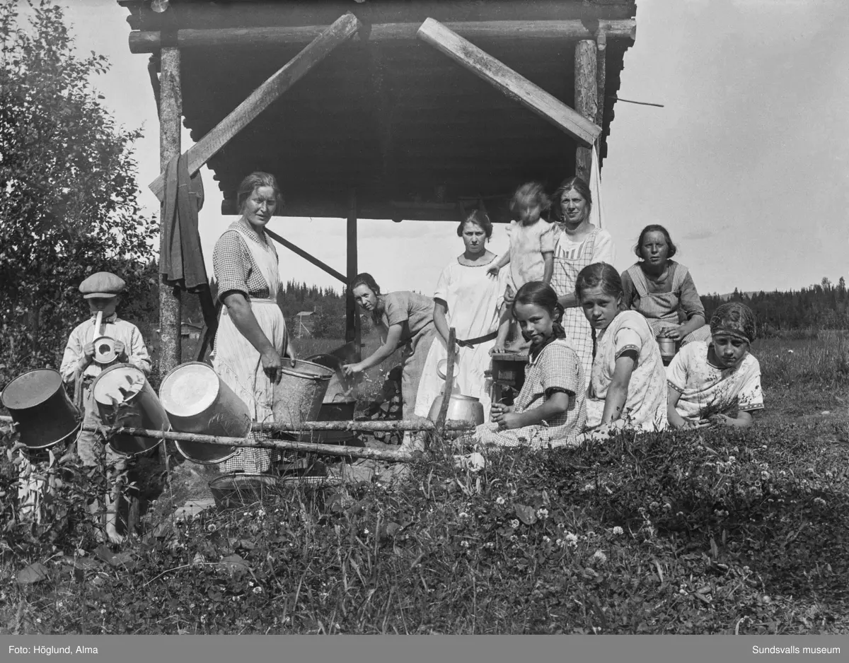 Kokhus vid en fäbodvall. Längst till vänster Per Höglund, till höger en okänd flicka samt Irma och Ingrid Höglund. Övriga är Helmi Larsson, Hilma Höglund, Märta Björk, Adelia Larsson samt två oidentiferade.