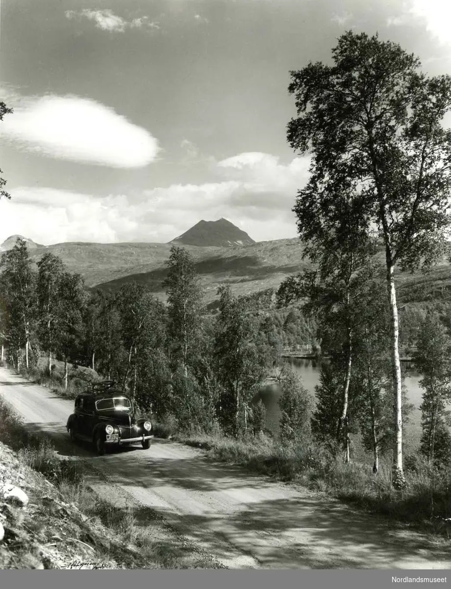 Natur. 
Sulitjelma-toppen sett fra nåværende fylkesvei som her passerer Emmavannet. Bilen var en Ford personbil som tilhørte Arne Furnes. (Muligens en førkrigsmodell som kom frem i dagens lys etter mai 1945?) 

Foto. Ukjent.