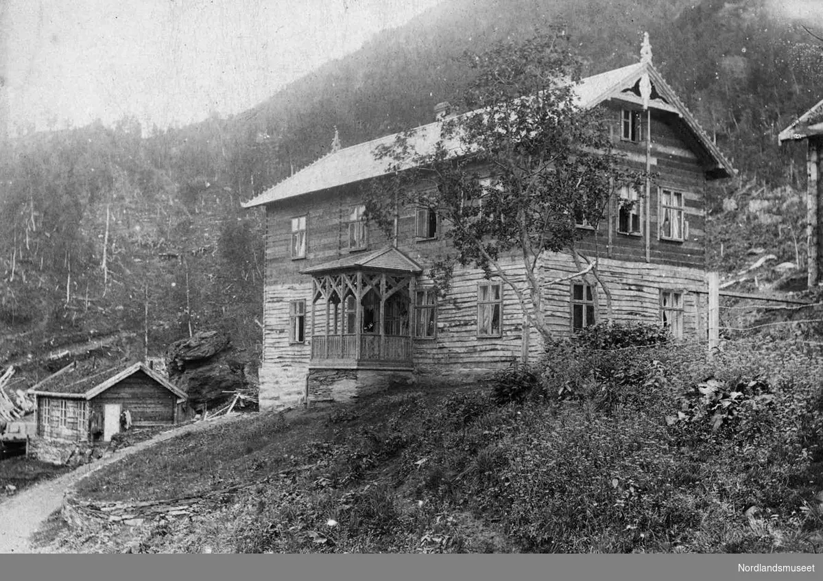 Furulund. 
”Villa Mons Petter” Dette huset var innflytningsklart da ing. Anfindsen kom hit i 1892. Når huset ble påbegynt bygget er ikke kjent, men det fortelles at huset fra først av var ment bygget i en etasje med tanke på å være et bryggeri for øl. 

Det ble derfor bygget i nærheten av Furulundsbekken. Da Persson fikk høre at slikt ikke var tillatt her tillands og da det var ansatt en familiemann som trafikksjef/maskiningeniør så ble huset bygget om og innredet som funksjonærbolig. 

I 1902 ble huset utbygd med nok en leilighet til stedets prest i andre etasje. Prestene i Sulitjelma bodde i husets frem til 1960 da det ble bygget egen prestebolig ved siden av kirken. Til høyre ses Kirkhus-brakka (ca 1887) mens det lille huset til venstre er Folkebadet (1898). 

Badet brant ned ca 1915. (Kirkhus-brakka skal opprinnelig ha stått tett ved der ”bryggeriet” ble påbegynt. Senere da ”Villa Mons Petter” ble påbegynt ble brakka flyttet nærmere ”Gartnermyra”. 

Senere ble brakka igjen flyttet og ble senere kjerne i en ny funksjonærbolig, ”Hagen-villaen”, der vi husker at hytteingeniør Lorents Lorck Hagen bodde. En snekker som i de siste årene har utført arbeid i dette huset forteller at tømmerdelen av det gamle huset fortsatt kan befinner seg inne i denne boligen.) 

Foto Ukjent.