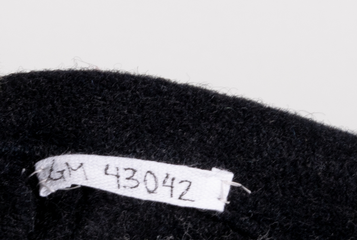 Djupt mörkblå bussarong med sjömanskrage. Två fickor på bröstet samt tygemblem med svensk flagga. Kragen har två fastsydda tygemblem med texten "I.O.G.T.".