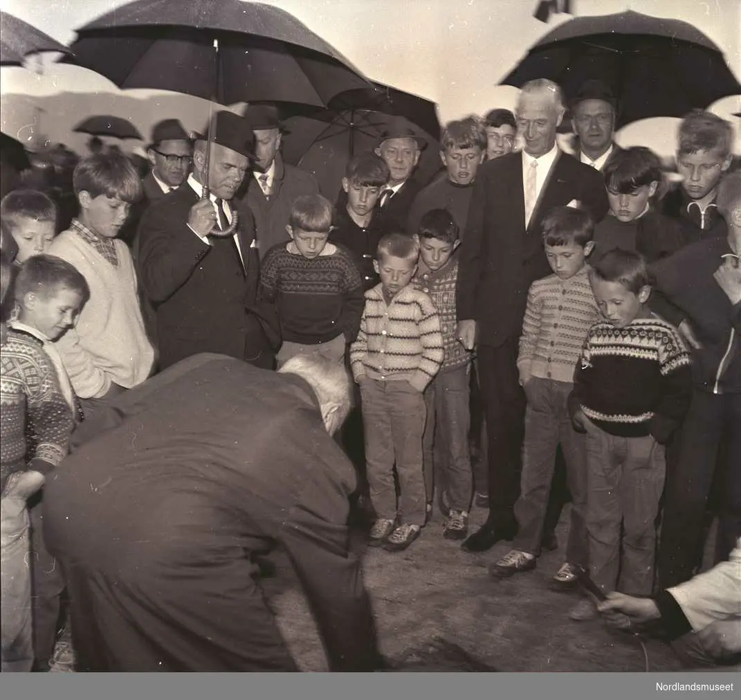 Bildet ble tatt i forbindelse med artikkel i Nordlands framtid 9. juni 1967.  Fra artikkelen: "Grunnstein på Fauske. Det var stor glede på Fauske da grunnsteinen til det nye Fauske gymnas ble lagt ned. Skoledirektør Olav Nyaas foretok den høytidelige handlingen, som vi har avbildet over".