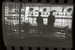 Fotografi av en kjøpmann og en kvinne som står bak to småhyl