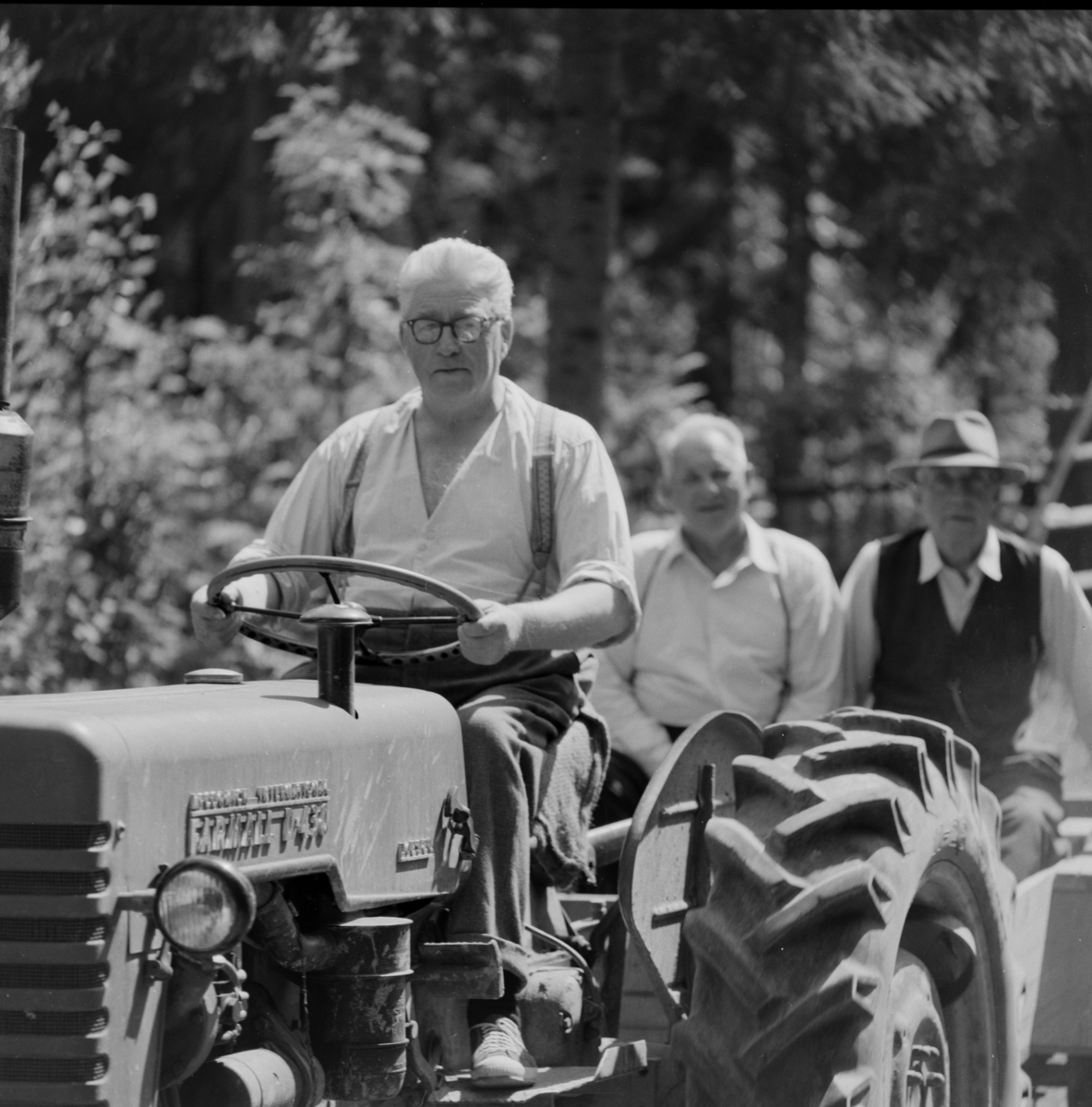 Tre menn på traktor med henger. Henry Nordby, Emil Egner og Ole Stokker.