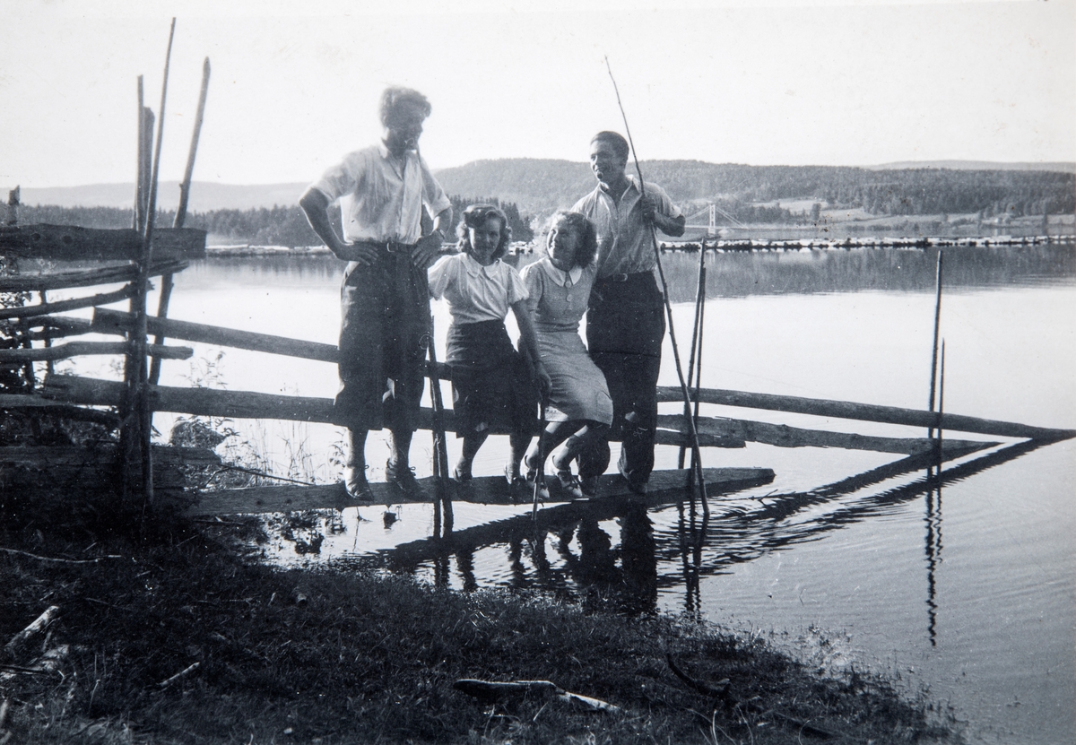 Gruppe 4 ungdommer på sykkeltur til Nes H. i 1939. Fra venstre: Arne Furulund (1919-2002), Eva Elisenberg (1917-1999), Gerd Hansen og Oddvar Hagelund. Her stående på en skigard som går ut i Mjøsa. Framnesbrua sees i bakgrunn.