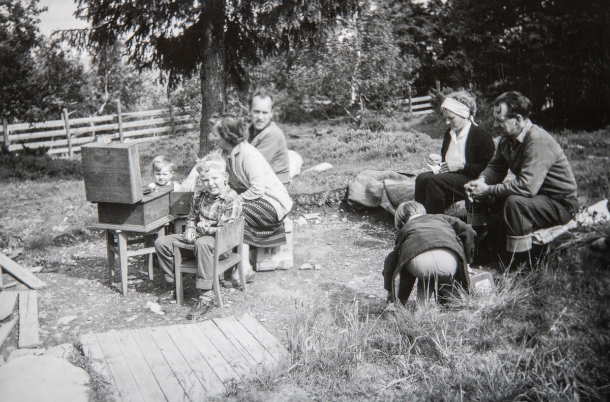 Familien Furulund på hyttetur. På Henrik Furulunds hytte på Grunnåsen i Ringsaker. Hytta hadde navnet "Fisut". Fra venstre: Trond Furulund, Vidar Furulund, Eva Furulund, Arne Furulund, Wenche Furulund, Kristine Furulund og Knut Furulund. Sitter å hører på en sveivegramafon, platespiller.