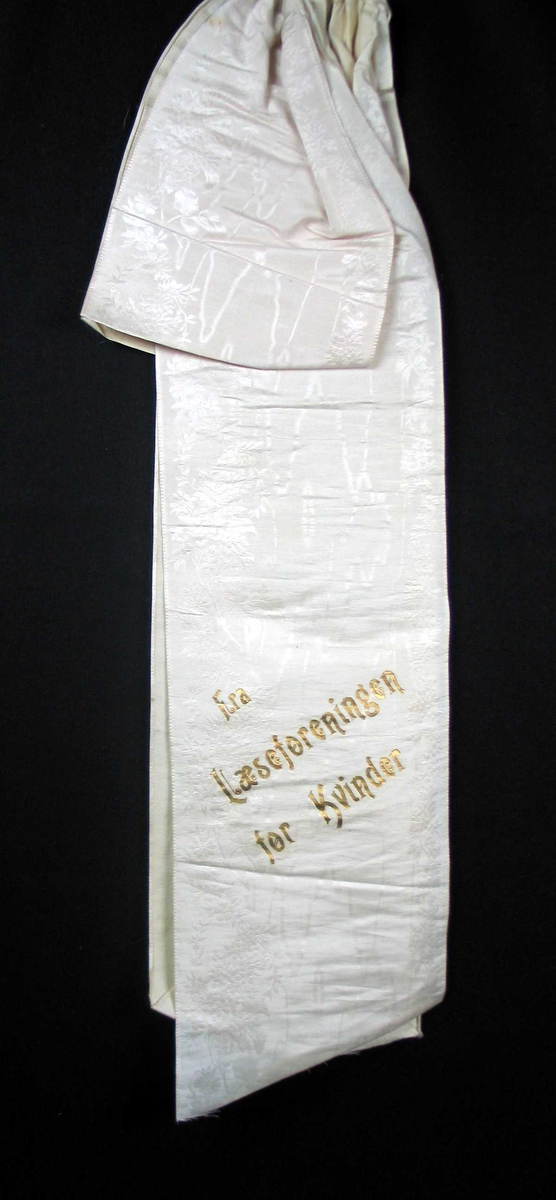 Begravelsessløyfe i hvit silke med tekst i gull.
