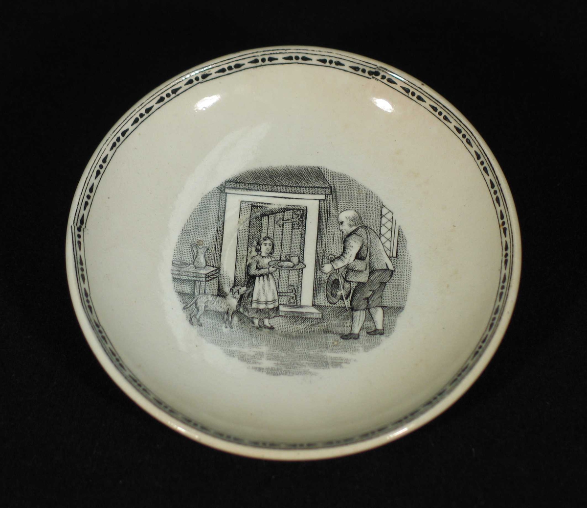 Hvit skål med svart bord ytterst og trykt motiv i midten.