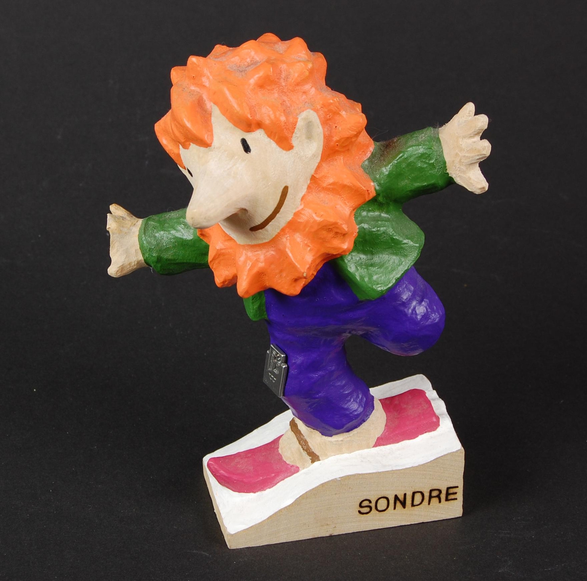 Sondrefigur av tre. Figuren fremstiller en trollgutt (Sondre) som står på ski, tross at han har et amputert bein. Fingrene på den ene hånden er knekt av.