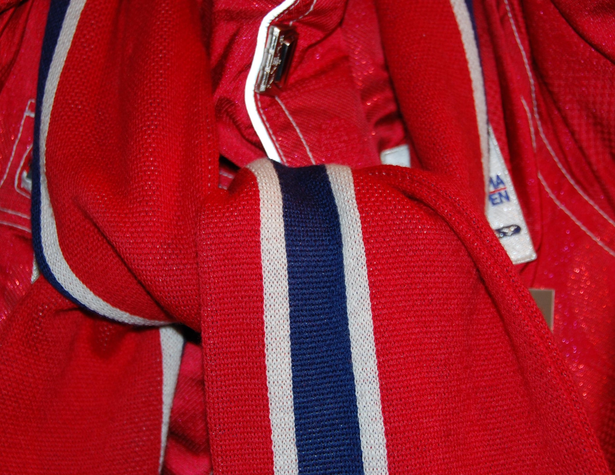 Rødt skjerf med striper i hvitt og blått.