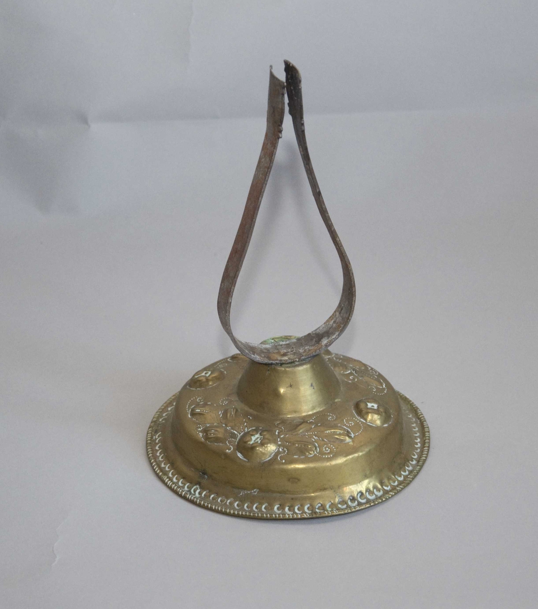 Messingstett med påsaatt jernbøyle som feste for lyset. Stetten har drevet og gravert blomsterdekor.