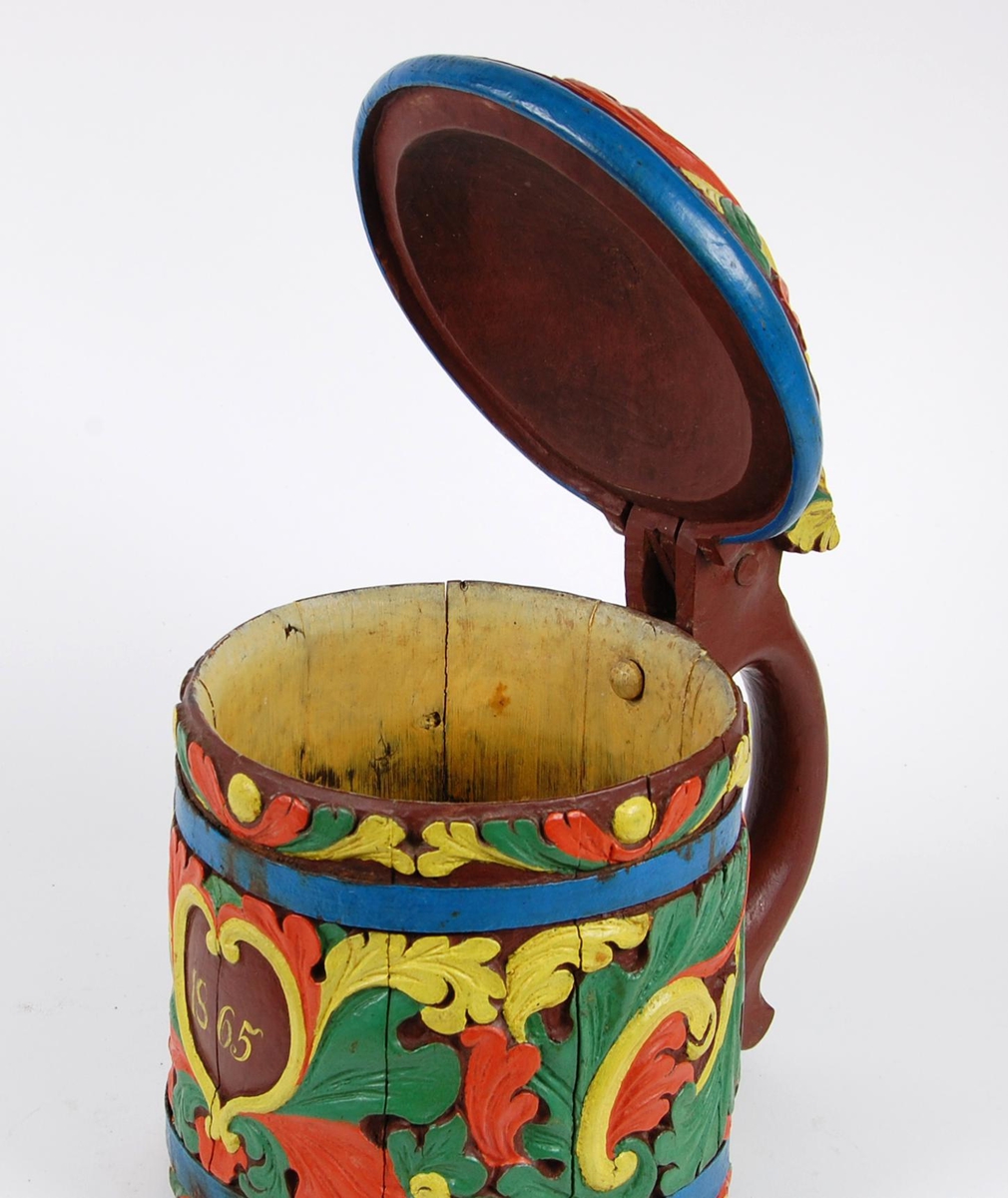 Kanne av staver. Lokk med gule, grønne og røde blader, blåmalt kant. Korpus med en blåmalt metallgjord oppe og nede, gule, grønne og røde akantusblader, brunmalt hjerteformet felt med innskriften 1865. Brunmalt hank. Tre røde og gule føtter.