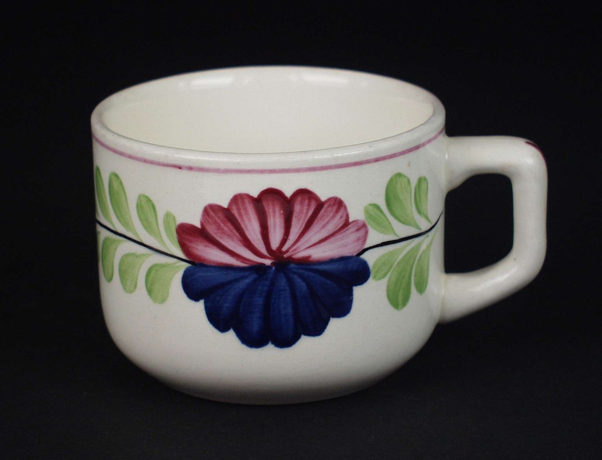 Deler av servise i steintøy og flintgods. Godset er hvitt med malt blomsterdekor. Rød og blå blomst i midten med en ranke av grønne blad.