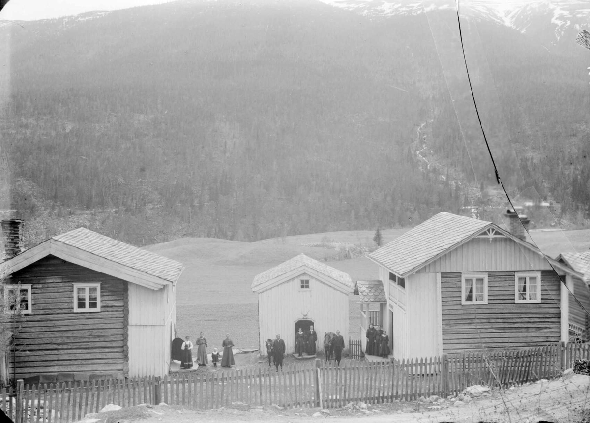 0206.1909. Gården  Aamodt. Bolighus, uthus, gjerde, kvinner, menn, barn, hester, skogkledd åsside.