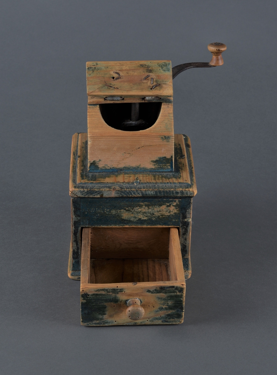 Kaffekvern i tre med kvadratisk bunn. Øverst et kaffehus med luke og innvendig kvern som dreies med en utvendig sveiv. Kvern og sveiv er i jern med en trekule til håndtak. Luka er hengslet til huset med streng. Nederst en utrekkbar skuff med trehåndtak. Kverna ser ut til å ha vært grønnmalt, men malinga er svært avslitt.