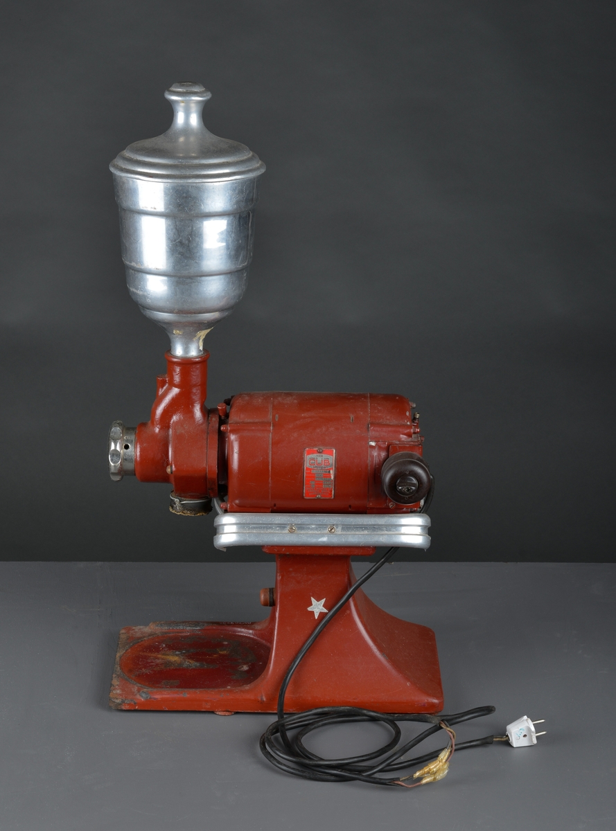 Motorisert kaffekvern som har stått i en landhandler. 
Kaffebønner helles i maskinen og males til kaffe, fortrinnsvis for kok-kaffe.

Det følger med en løs beholder for å samle opp den malte kaffen.

Maskina er rødlakkert, er slitt med noe rust og rester av olje eller fett.