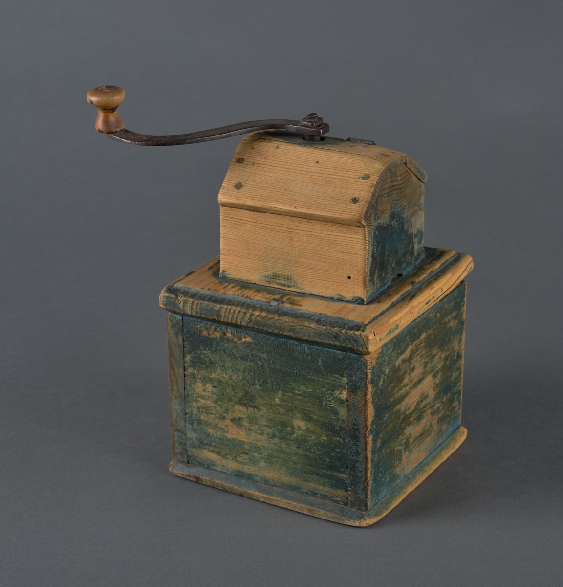 Kaffekvern i tre med kvadratisk bunn. Øverst et kaffehus med luke og innvendig kvern som dreies med en utvendig sveiv. Kvern og sveiv er i jern med en trekule til håndtak. Luka er hengslet til huset med streng. Nederst en utrekkbar skuff med trehåndtak. Kverna ser ut til å ha vært grønnmalt, men malinga er svært avslitt.